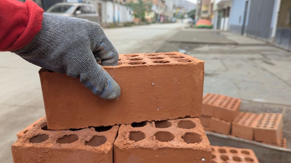 Maçon posant une brique creuse sur un mur