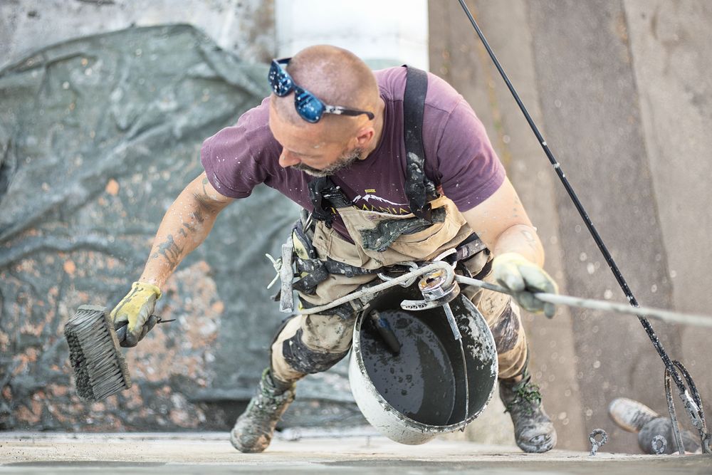 Façadier appliquant un enduit sur un mur en hauteur